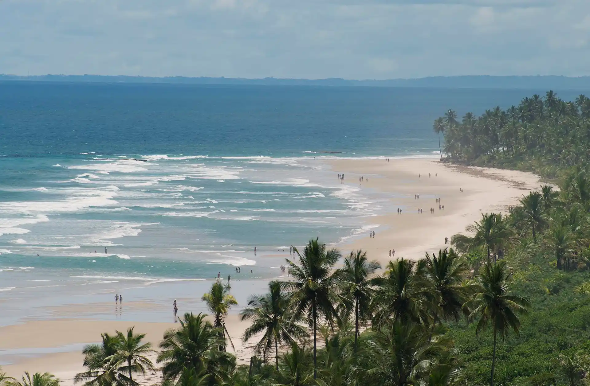 Itacarezinho vista do alto: a praia longa de areia clara, a arrebentação e o coqueiral até o horizonte