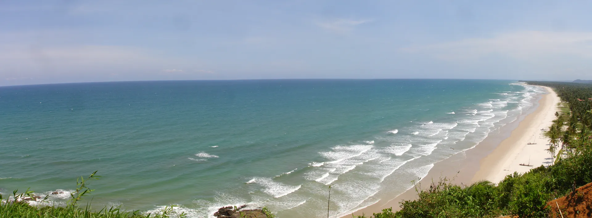 Itacarezinho em panorâmica: a praia longa de areia clara, o mar verde e o coqueiral