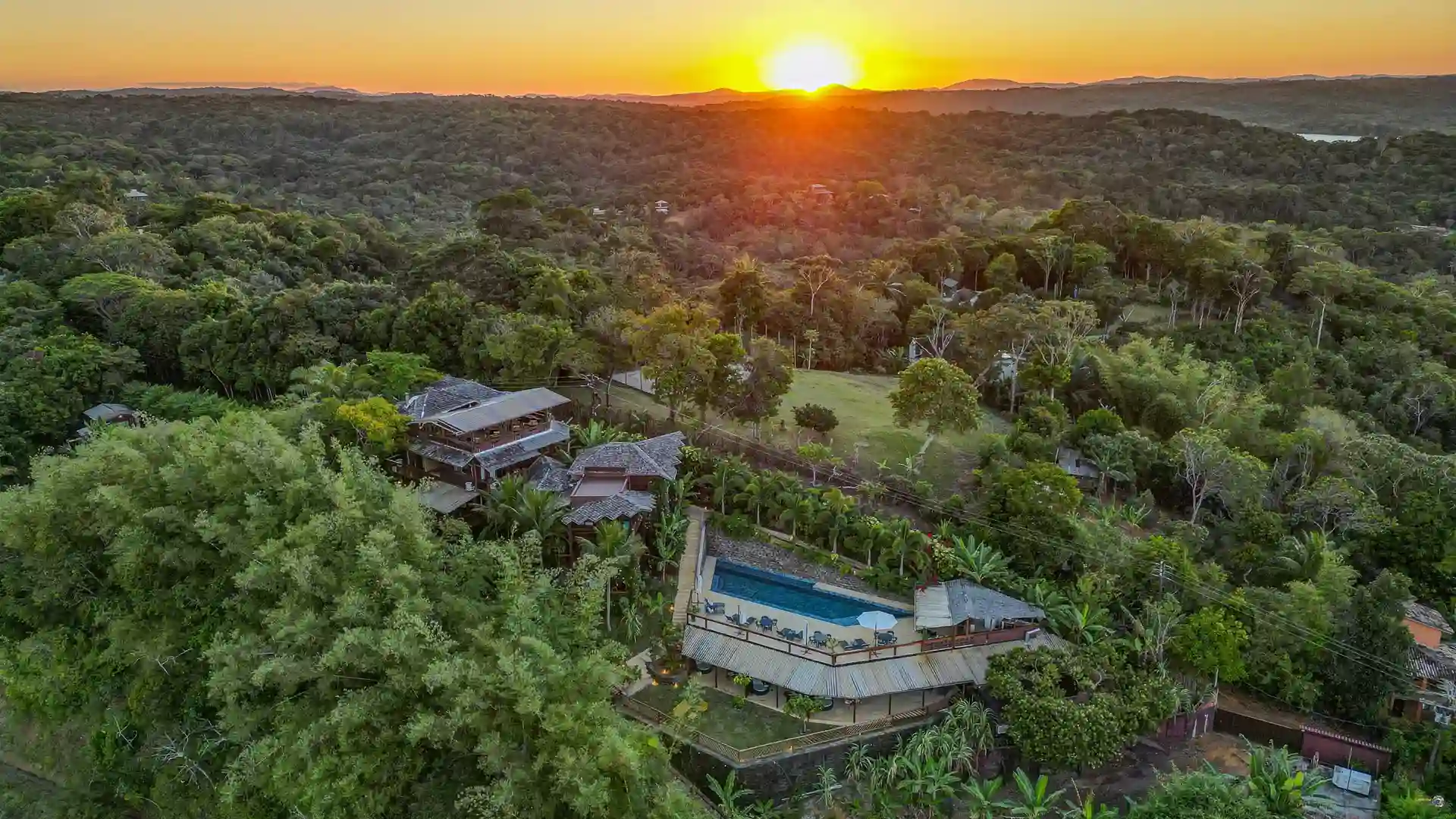 The low sun over the forest, with the hotel and the pool on the hilltop