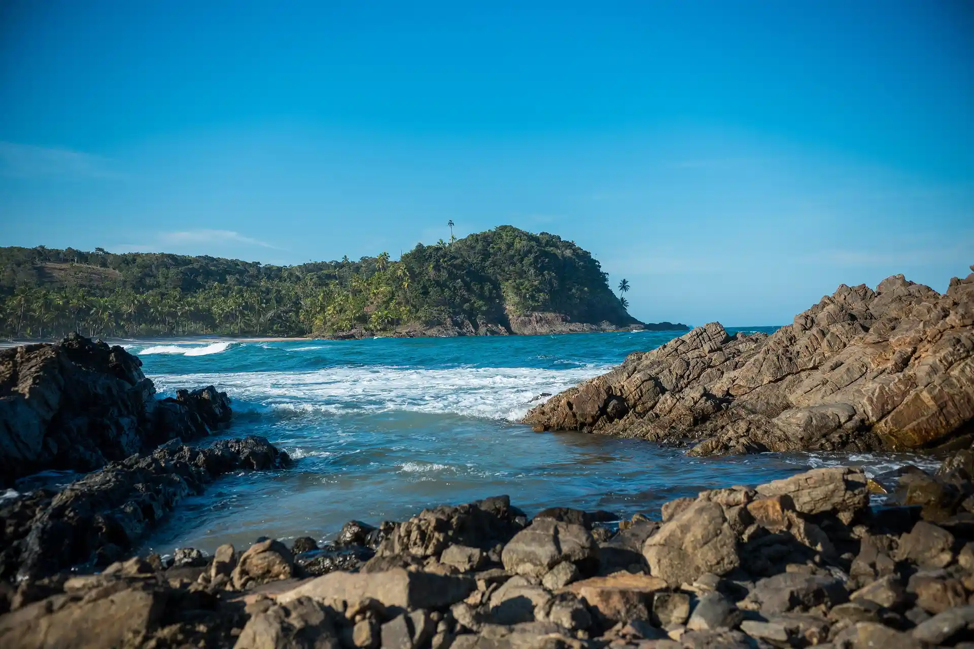 A Prainha, em Itacaré: a onda quebrando entre as pedras do canto e o morro de mata atrás