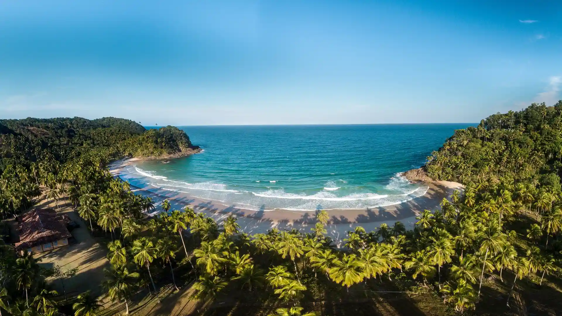 A Prainha vista do alto: uma enseada de areia entre dois morros de mata, com o mar verde