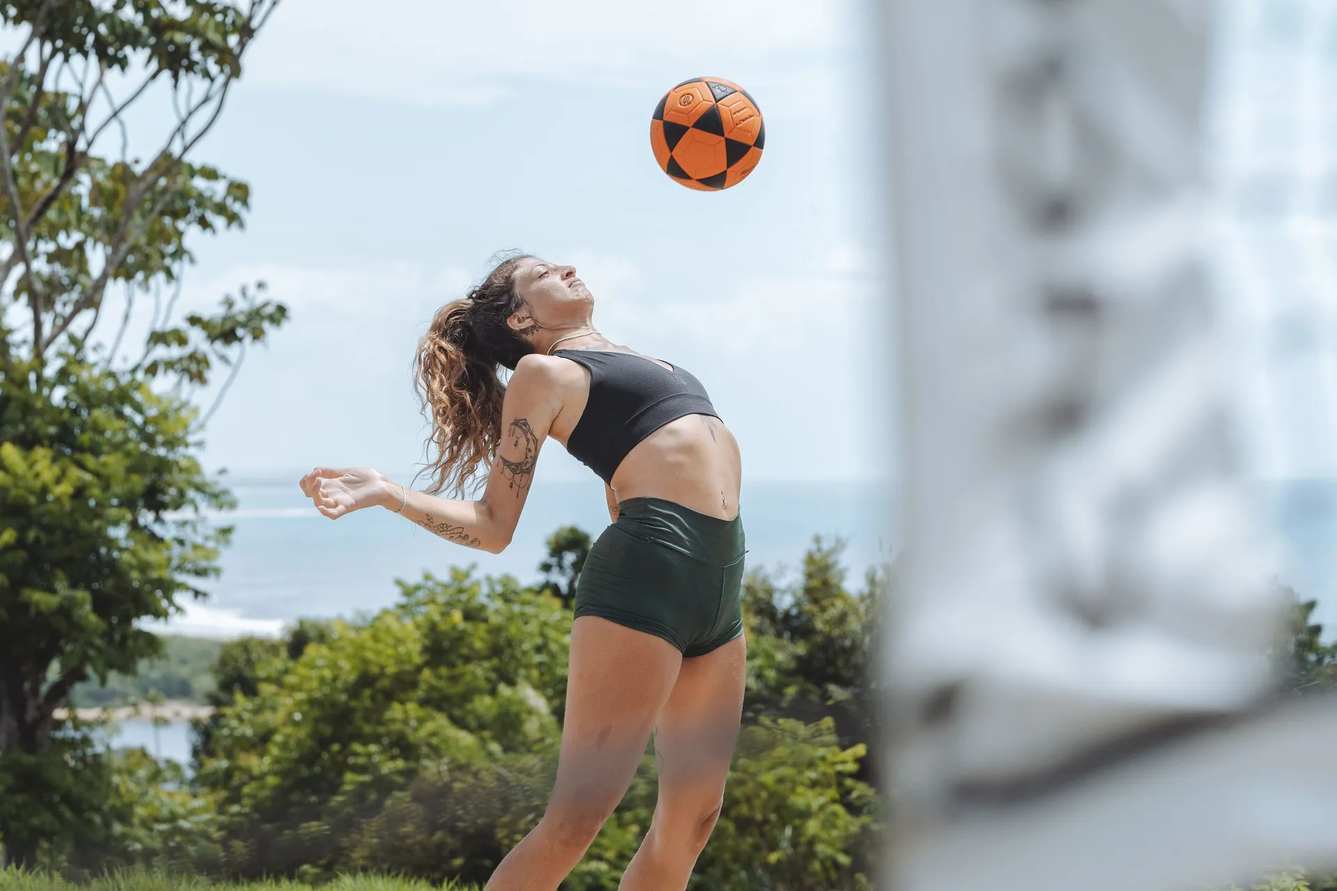 Jogo de beach tennis na quadra de areia do hotel, com a mata e a linha do mar ao fundo