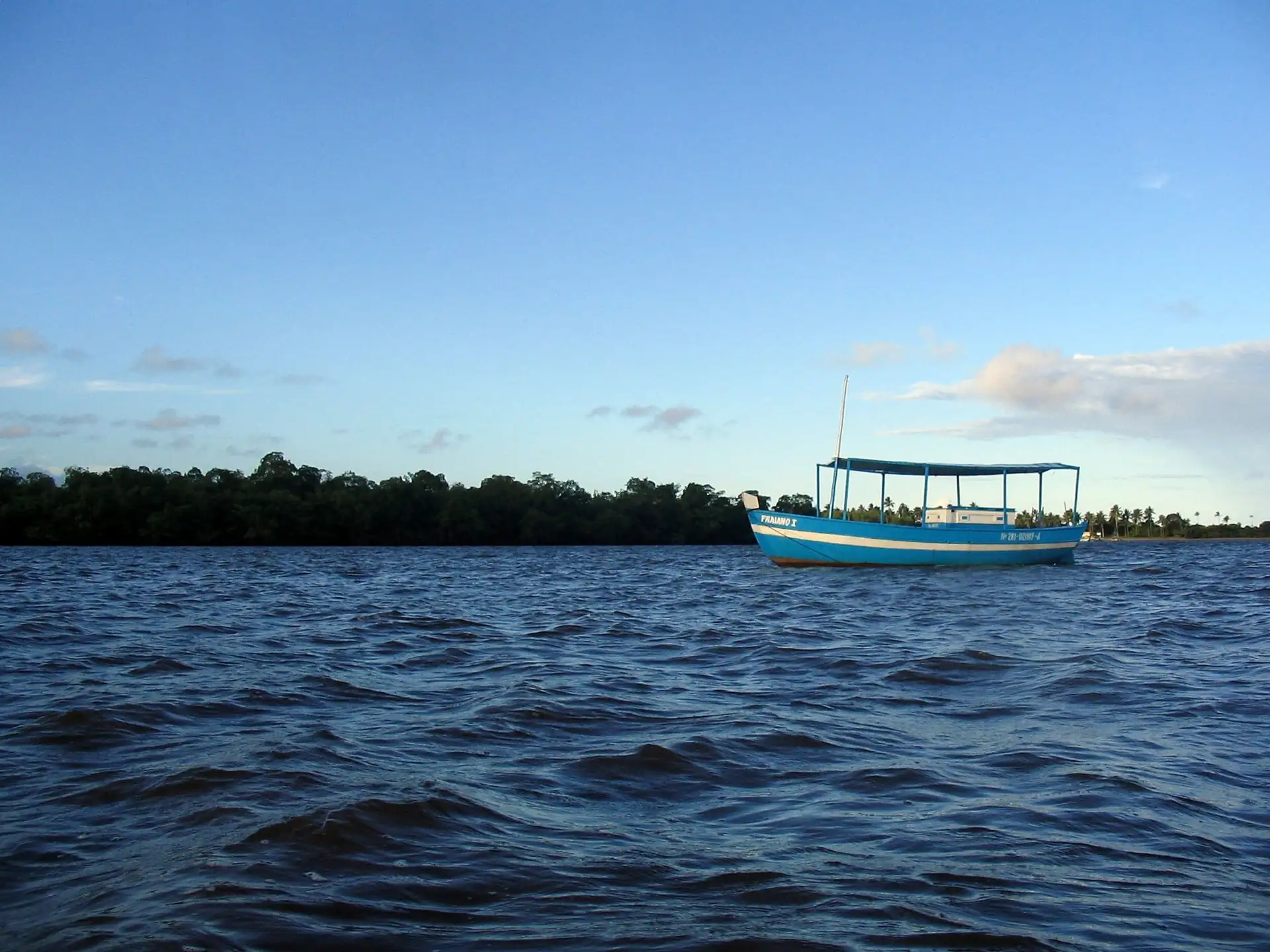 Barco de passeio navegando no rio de Contas, em Itacaré, com a mata nas margens