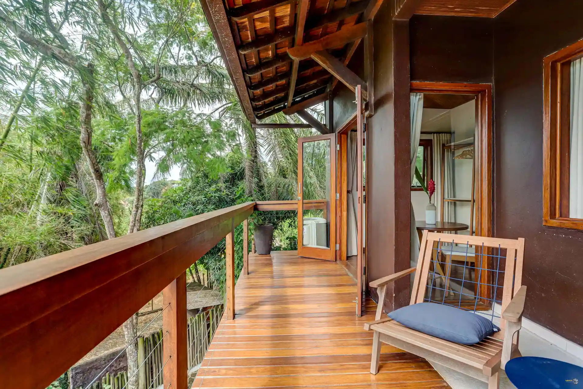 The balcony of a Semente suite, the wooden deck and the forest at the railing