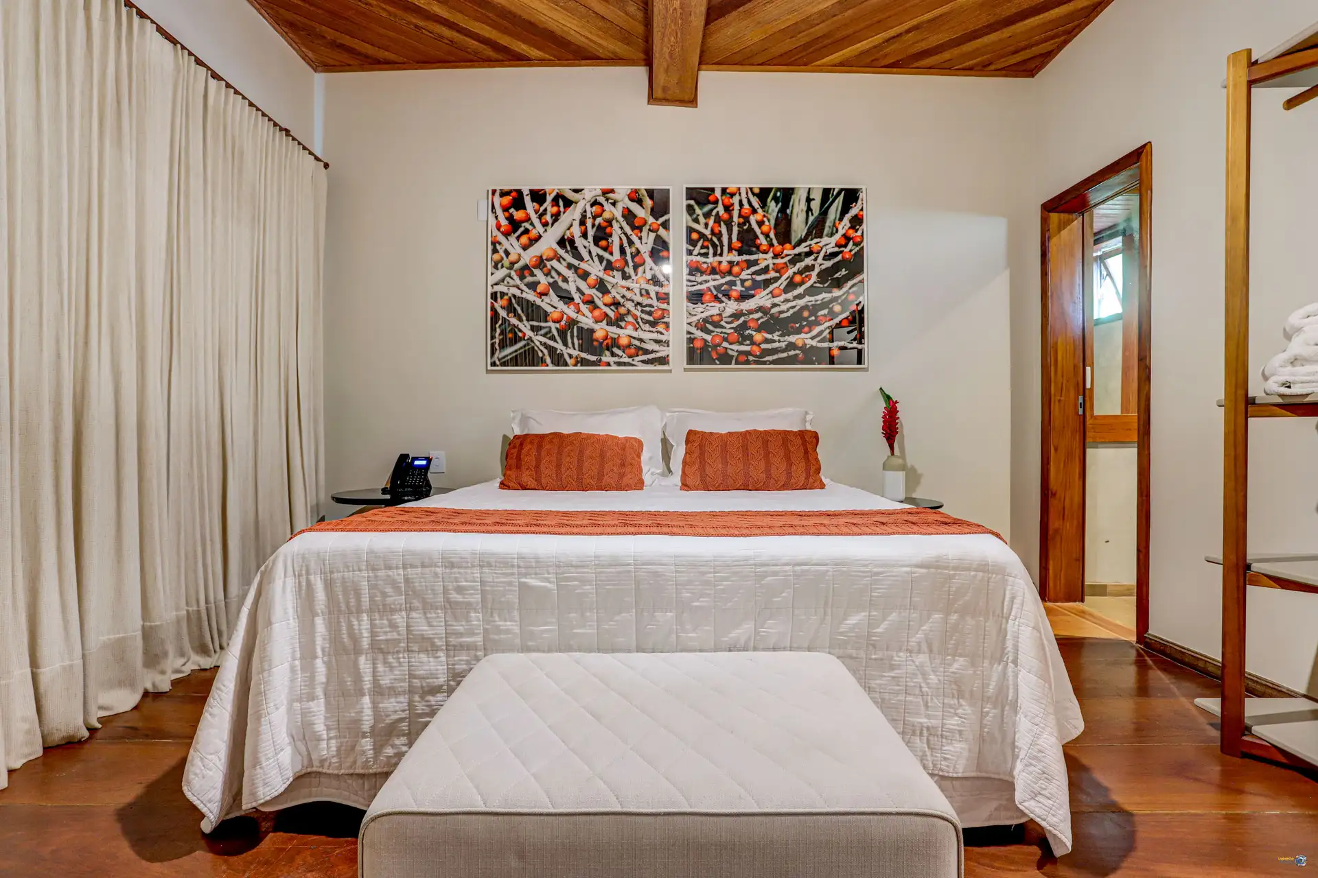 A cama queen size de uma suíte Torra, com os quadros de cacau na parede