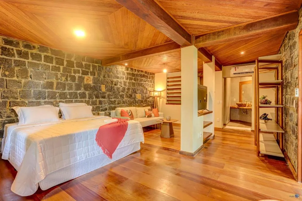 A Tulha suite: the stone wall behind the queen bed, and the sitting area and bathroom beyond
