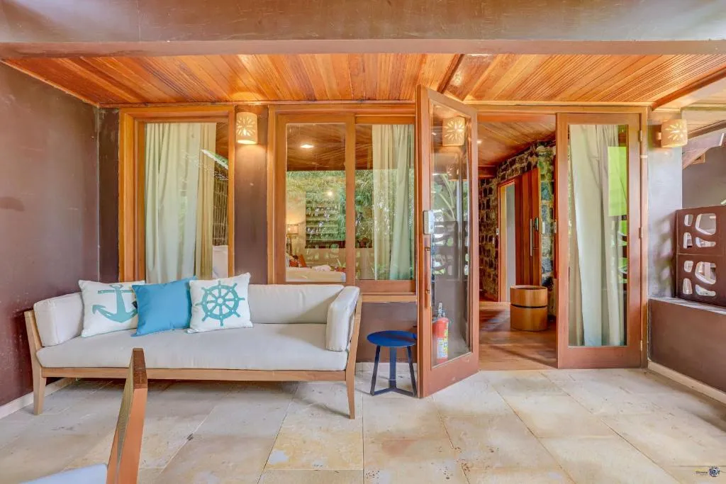 The covered balcony of a Tulha suite, with a sofa and the glass doors into the bedroom